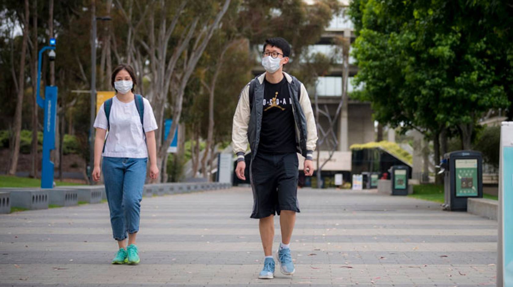 Two students walk with facemasks on