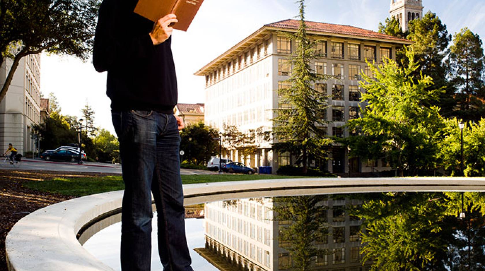 student reads book near Berkeley Campanile