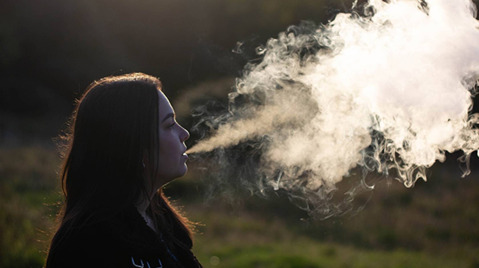 Young woman vaping big cloud of smoke