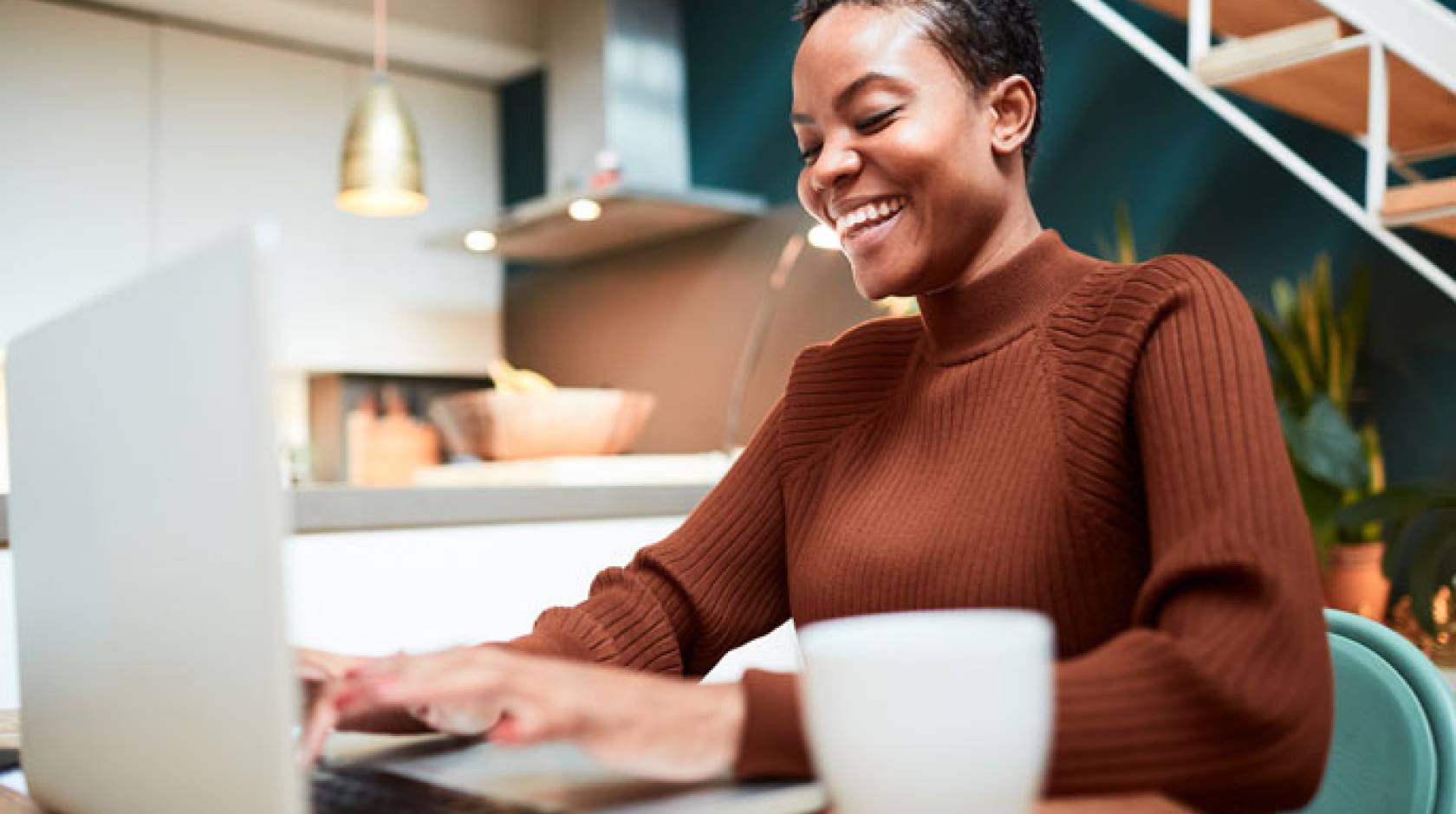 Young black woman laughing while looking at computer screen