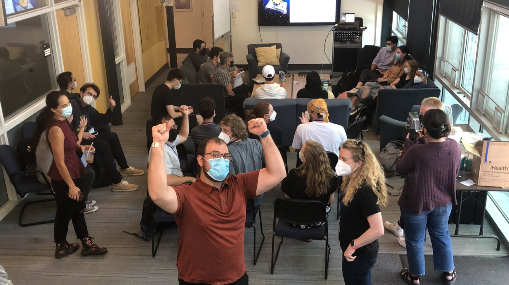 Astronomers cheering and gathered together to look at the James Webb Telescope images