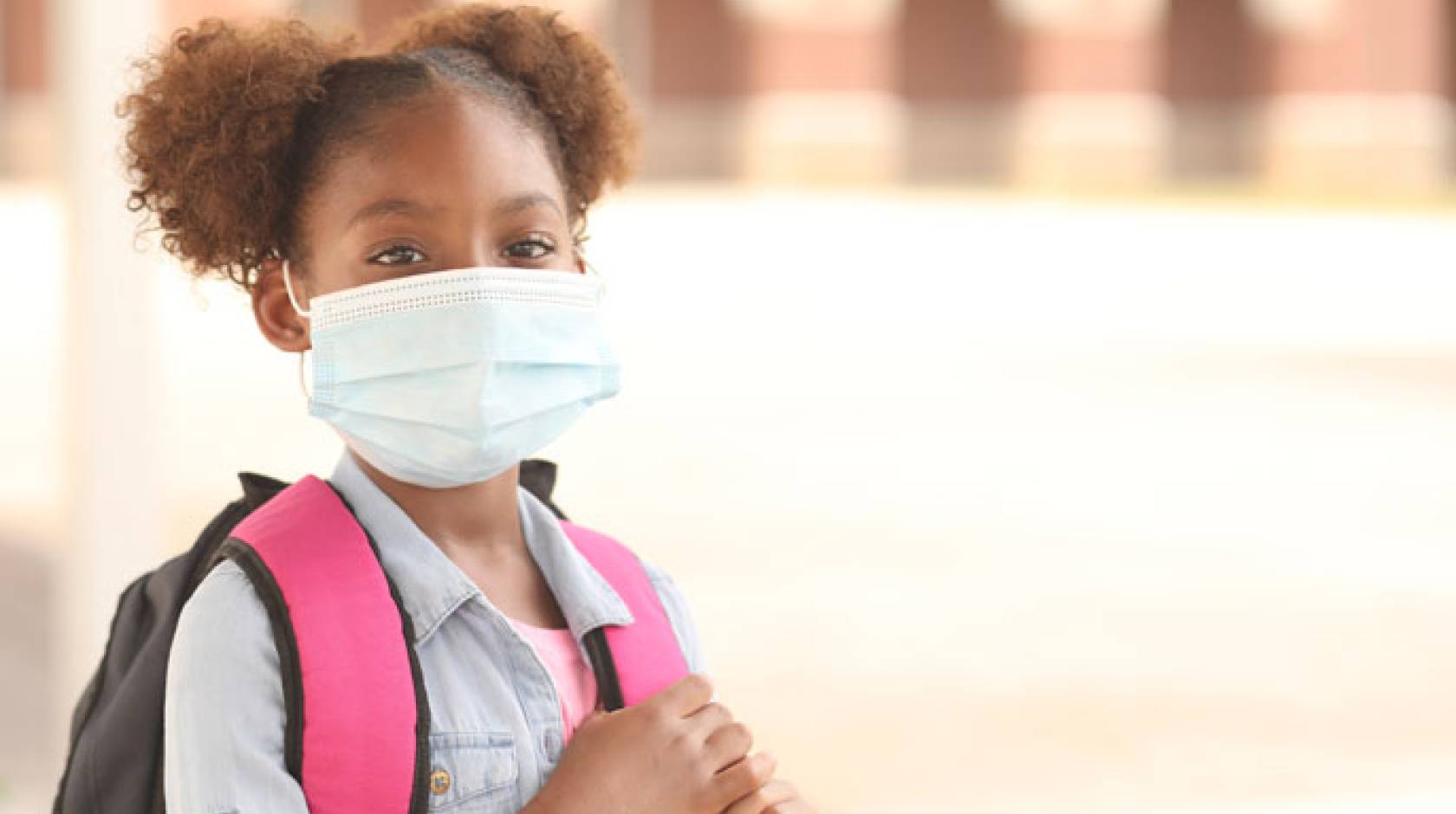 Young Black girl with a backpack in a mask