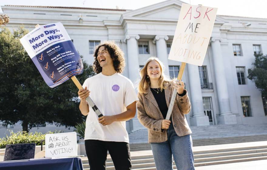 students on campus hold signs encouraging voter registration