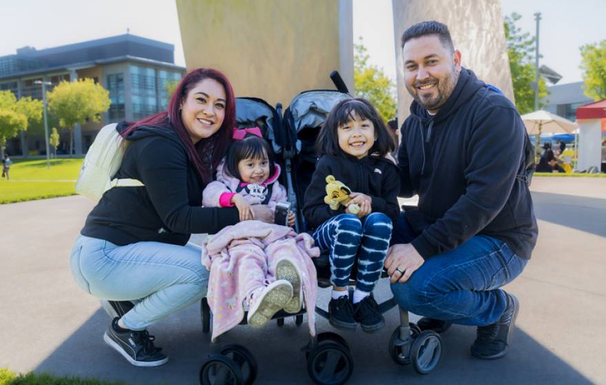 A family with two parents and two young children in a stroller