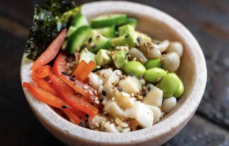 A poke bowl with vegetables, edamame, fish, sesame seeds and seaweed