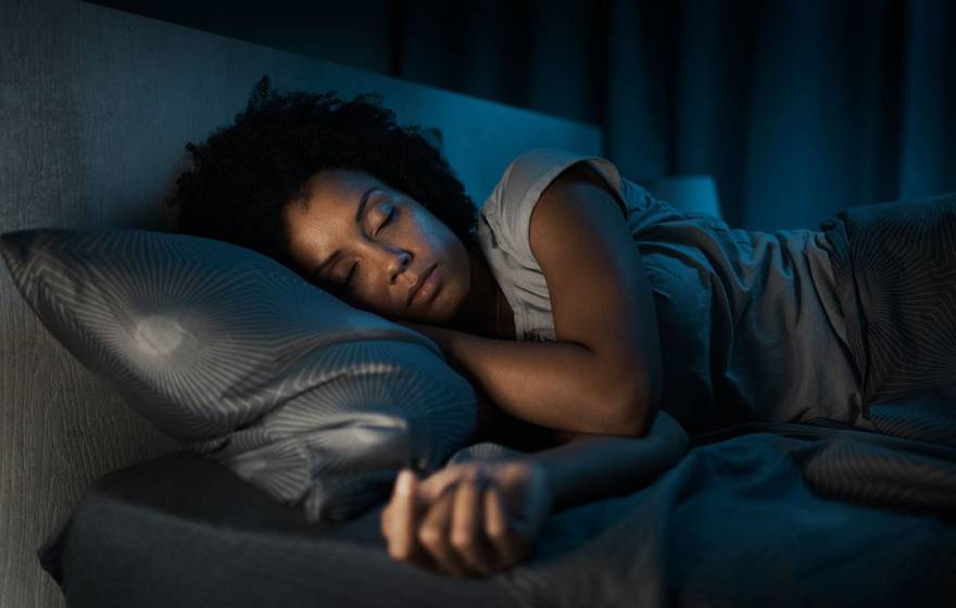 A person sleeping in bed in a dark room