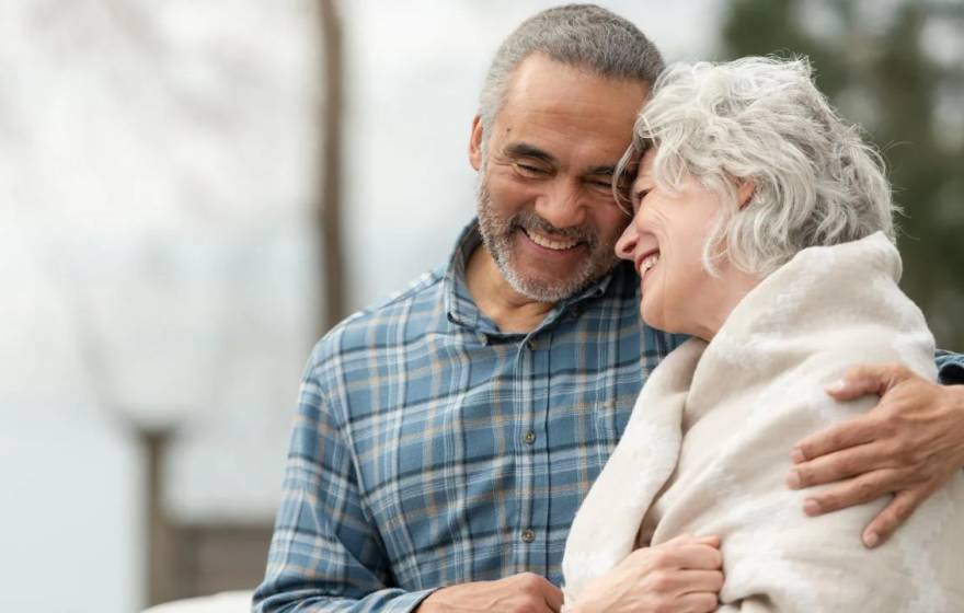 Older man and woman smile and embrace