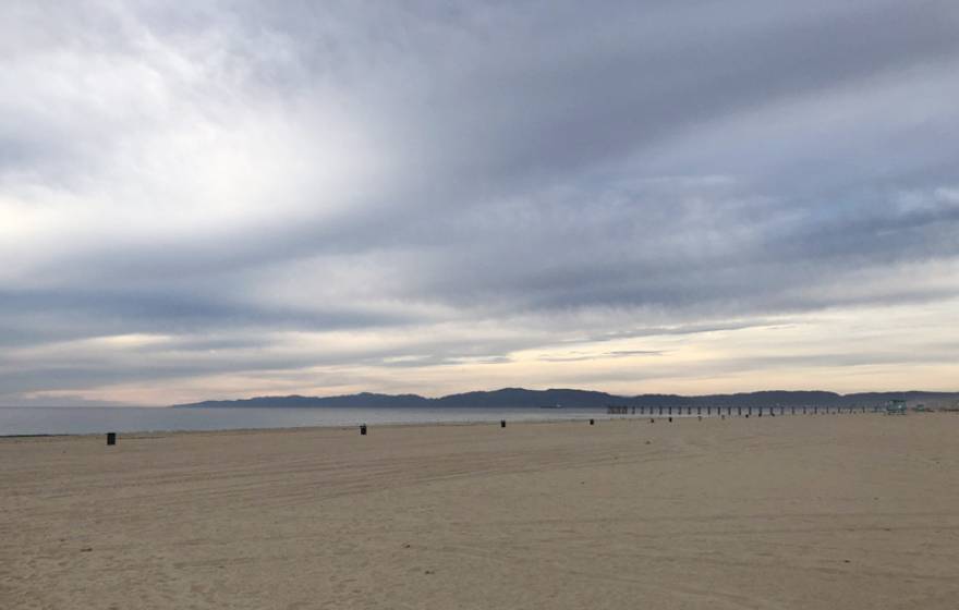 A wide-angle view of Hermosa Beach under a dramatic, cloudy sky