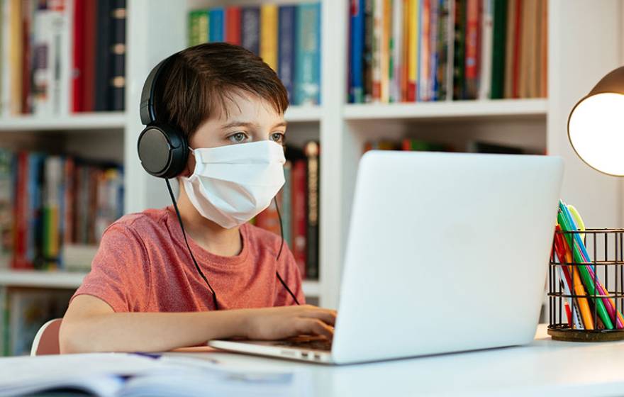 Boy in face mask working on a computer