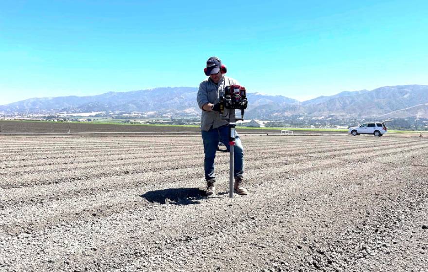 A man taking a soil sample in the middle of a dirt field