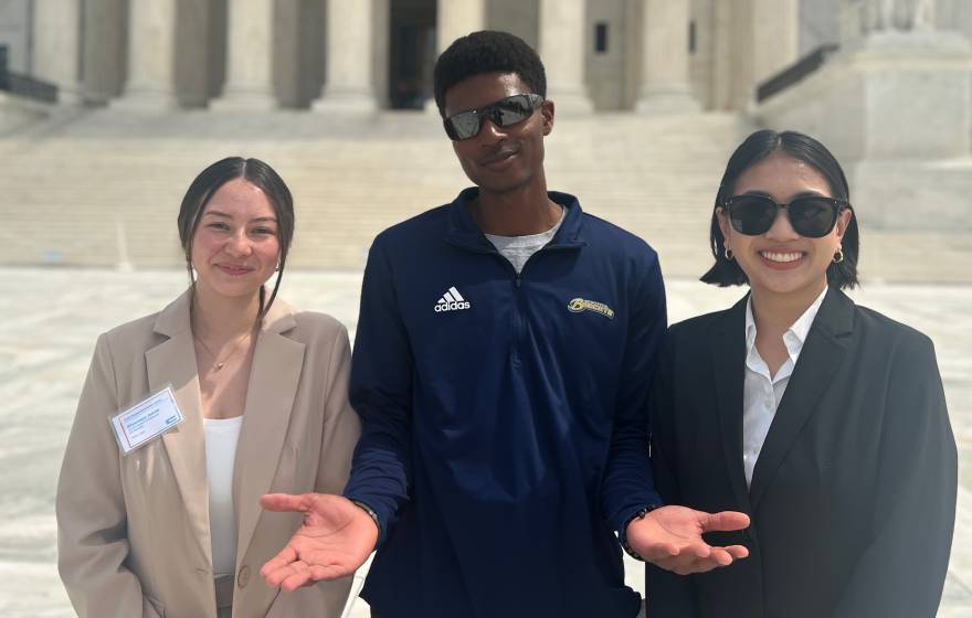 3 UCAN student ambassadors in business attire smile in front of the Capitol Building