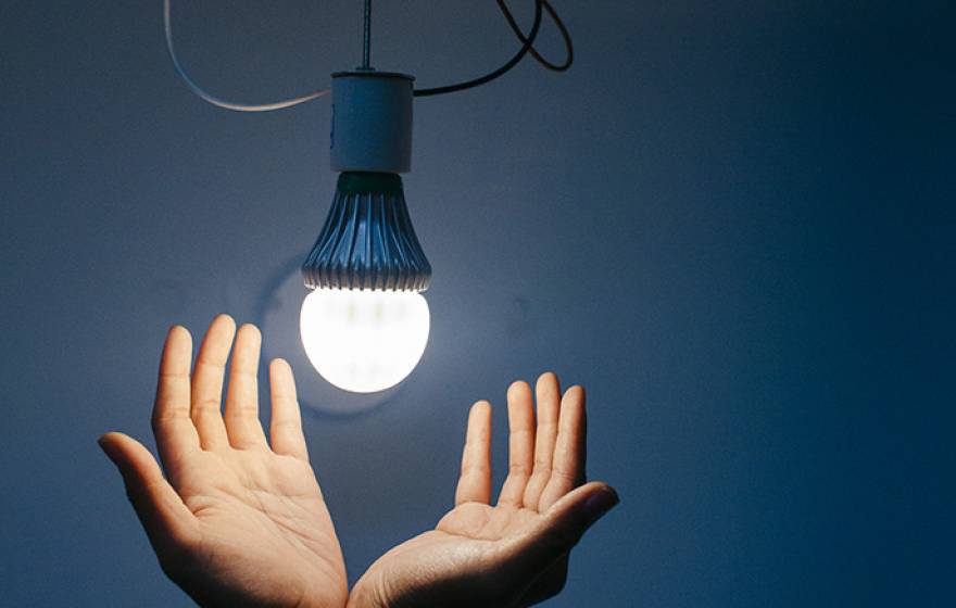 Hands below a light bulb
