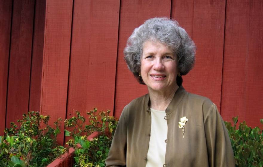 An older woman smiles in a portrait outside