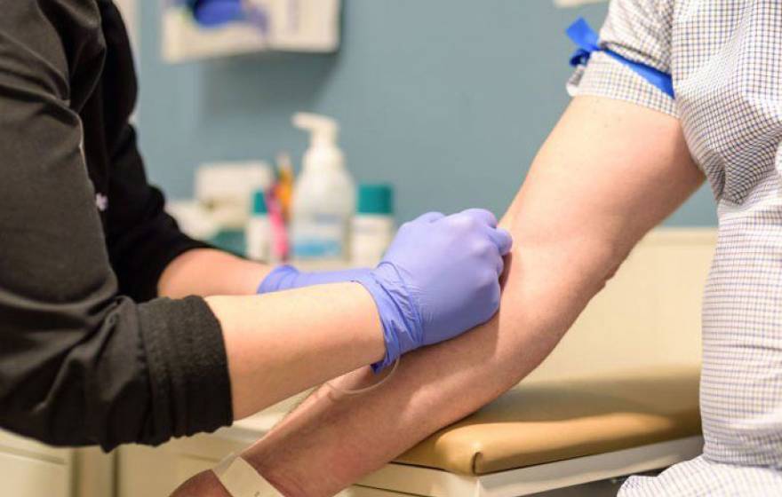 Someone taking blood from someone else in a doctor's office