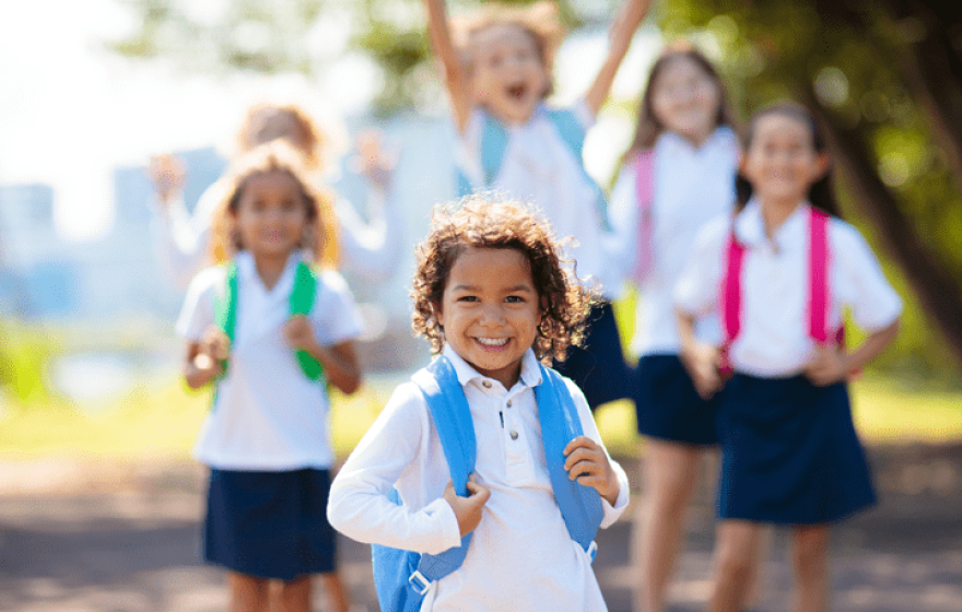 Interracial group of children of mixed age run and cheer on the first day of new academic year.