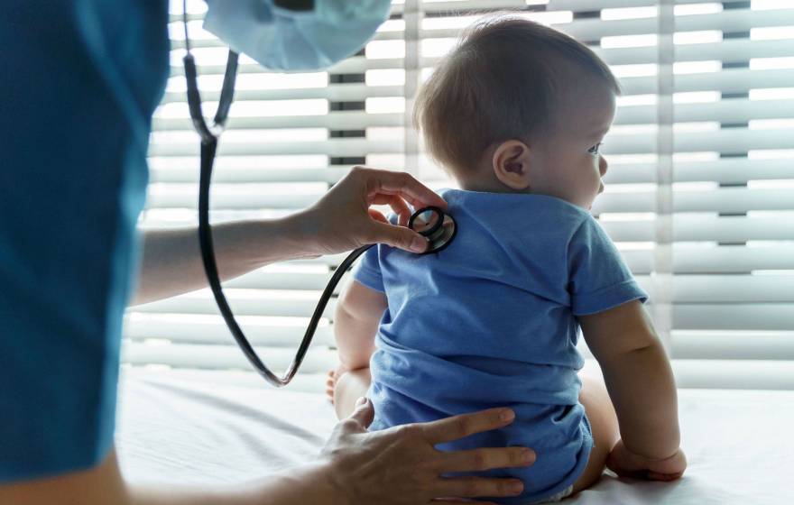 An infant getting checked by a pediatrician with a stethoscope