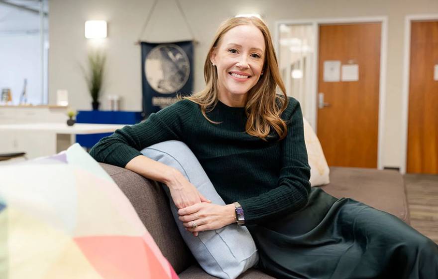 Brandie Nonnecke, seated on a couch, smiling at the viewer