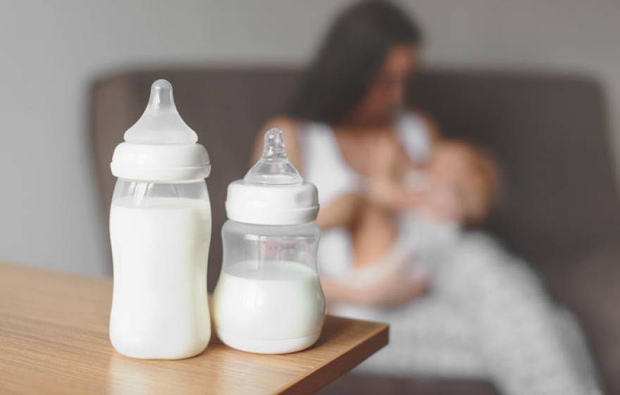 Breastmilk bottles in front of a mother breastfeeding