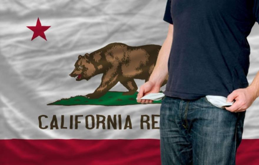 Man exposes empty pockets in front of a California flag