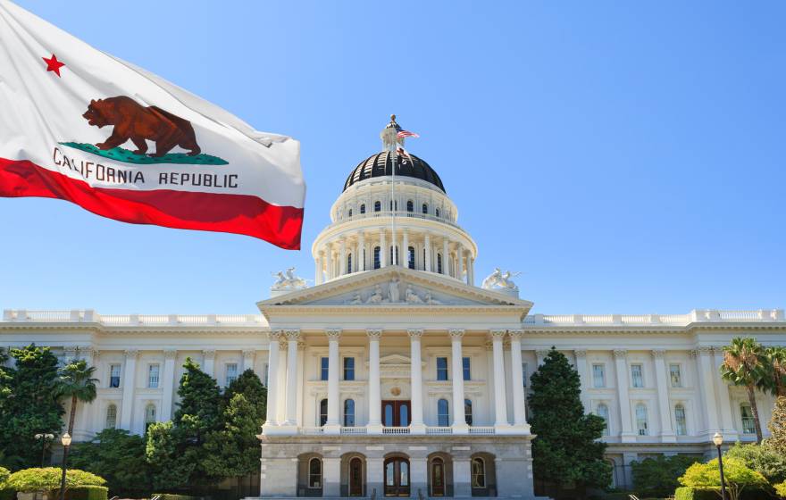 Sacramento capitol building with California state flag flying in front of it