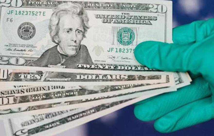 Gloved hand holding $20 bills