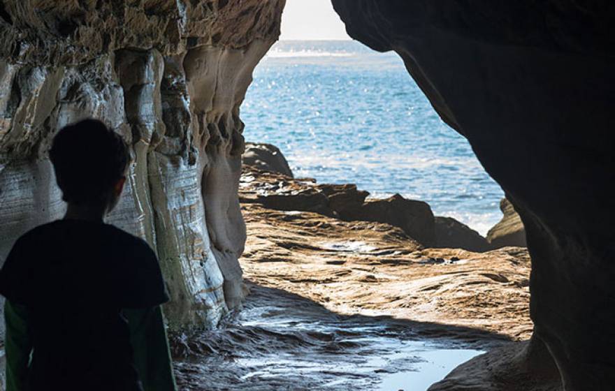 Person looking out from a cave at water