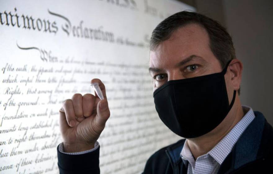 Chaput holds up a small object in front of the Declaration of Independence