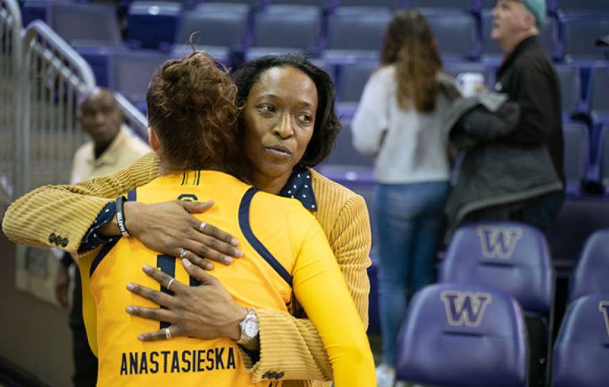 Charmin Smith consoles one of her players with a hug after a basketball game