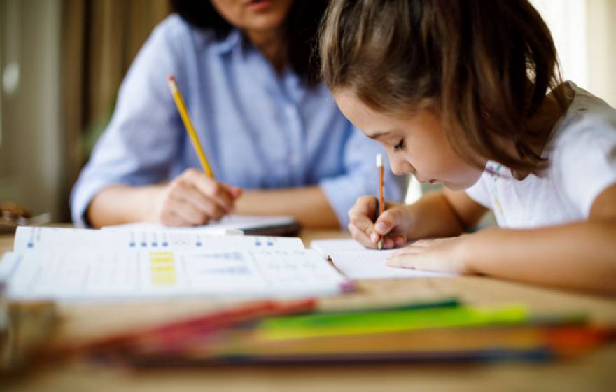 Young child doing homework with her mother