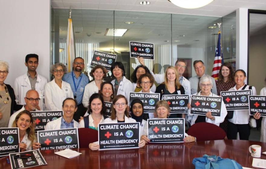 Varied group of people holding up climate change is a health emergency signs