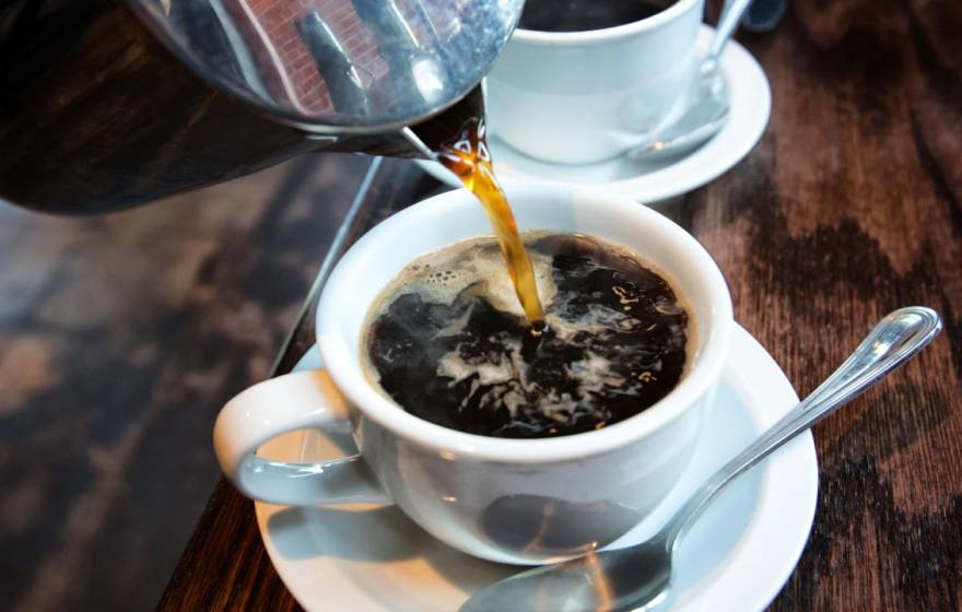 Coffee being poured into a cup, another cup behind it