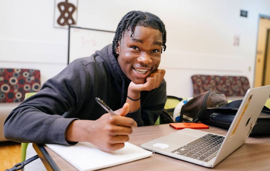 College student looks up from his notes and laptop with a quizzical look on his face