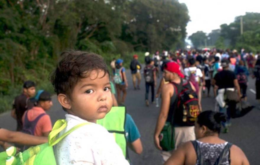 A child looks at the camera from among a group of migrants