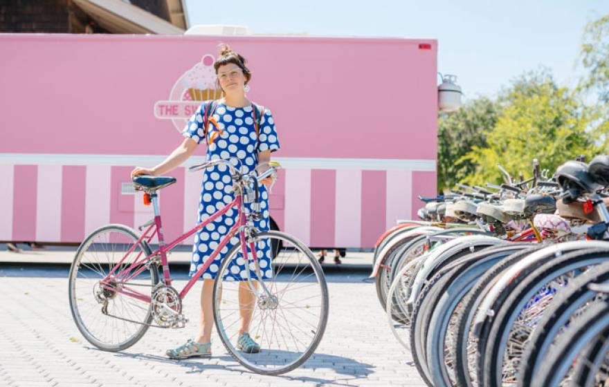 Woman in polka dot dress standing with bike at bike rack