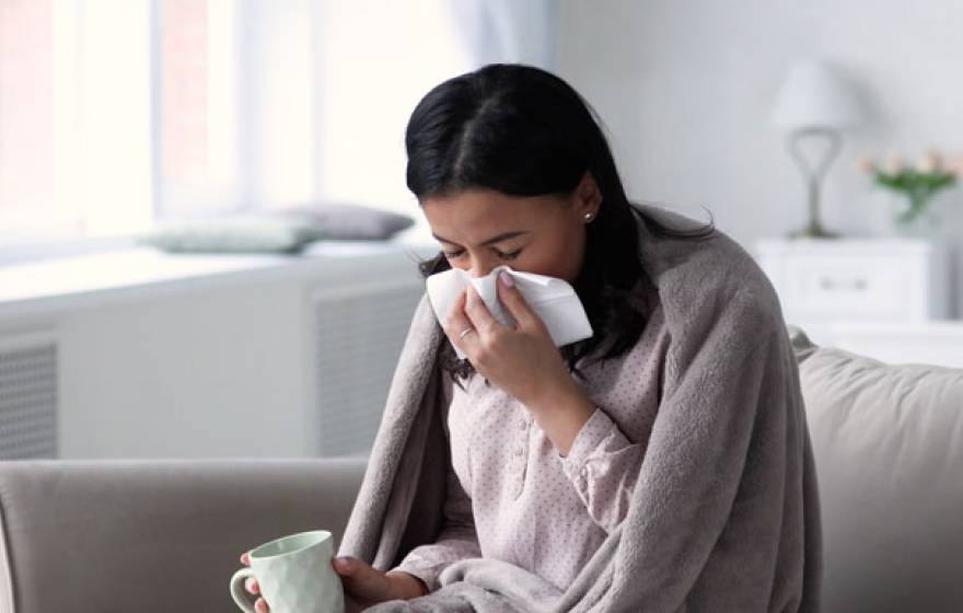 Woman sneezing on a couch