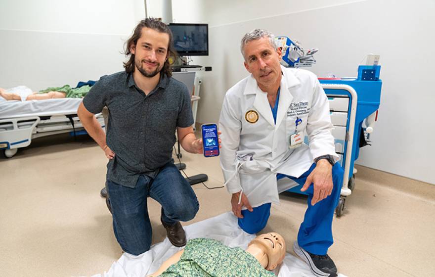 Medical student and a doctor kneeling over a CPR dummy with the app