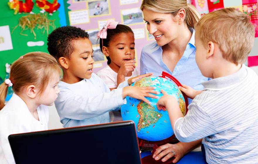 young children and teacher look at globe