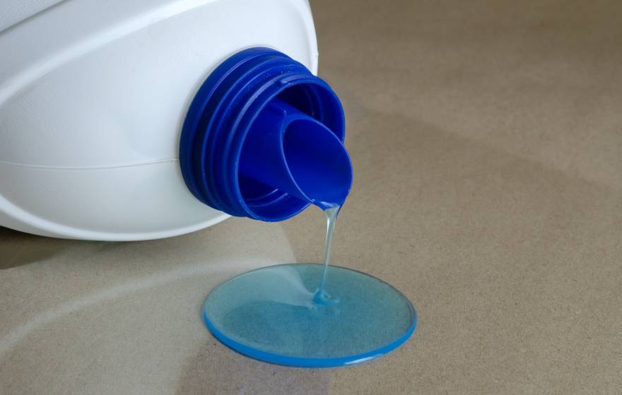 blue liquid spilling out of a plastic laundry detergent bottle