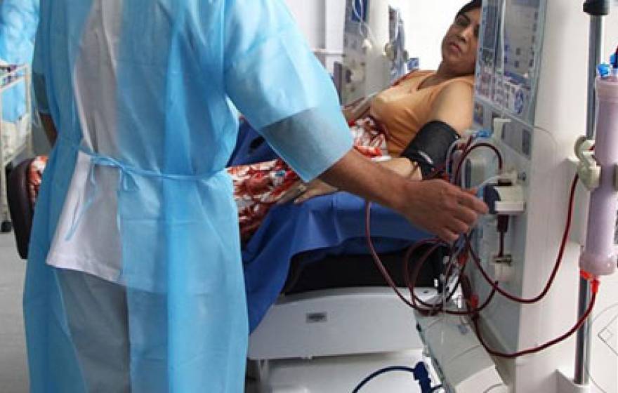 Nurse operating dialysis machine next to a woman