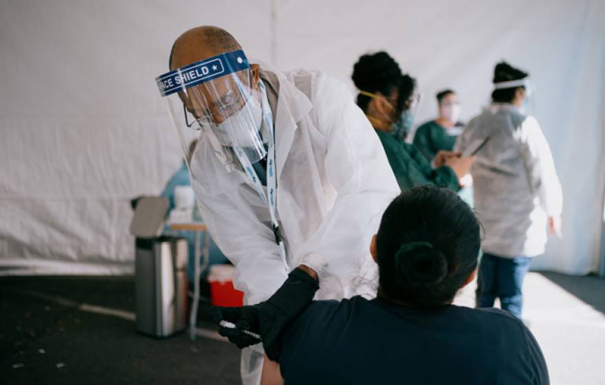 President Drake administers a vaccine to a woman at the community hub