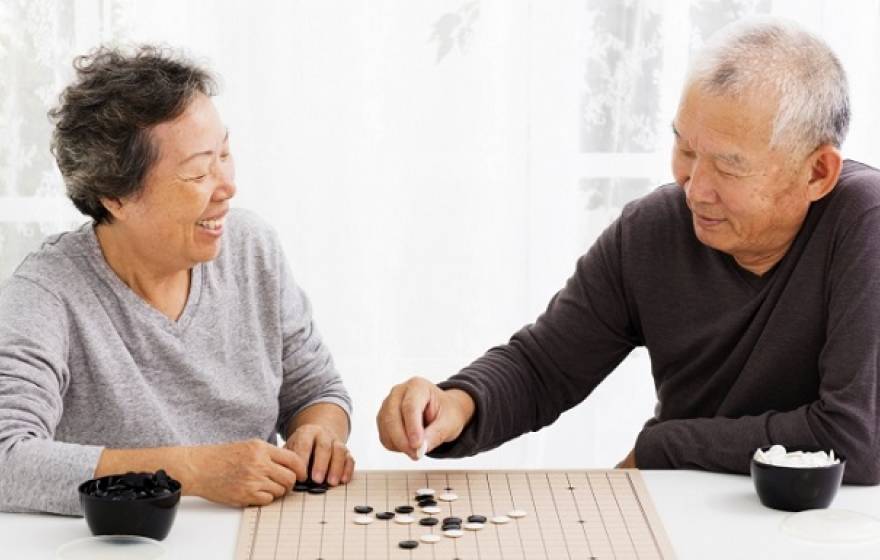 An elderly Asian couple plays a game
