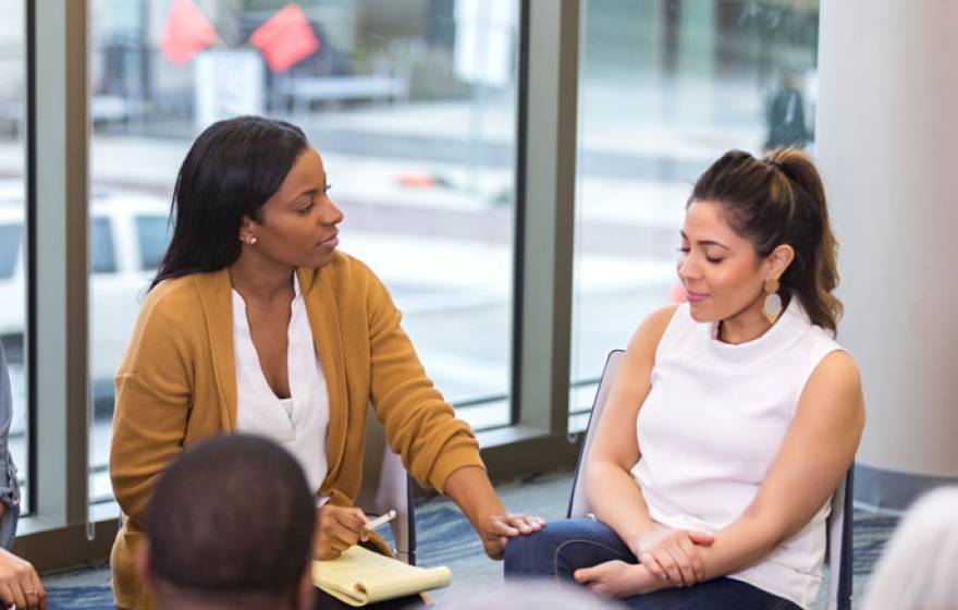 Woman comforts another woman while sitting in a circle