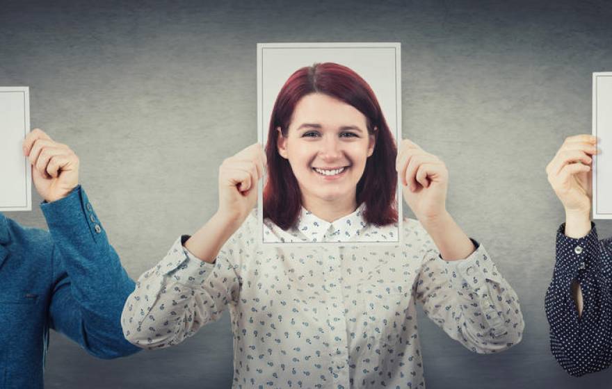 People cover their faces with photos of themselves smiling