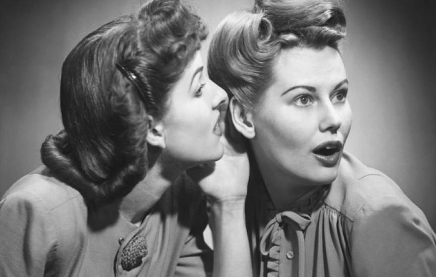 Two women in 50s hairstyles gossip in black and white photo