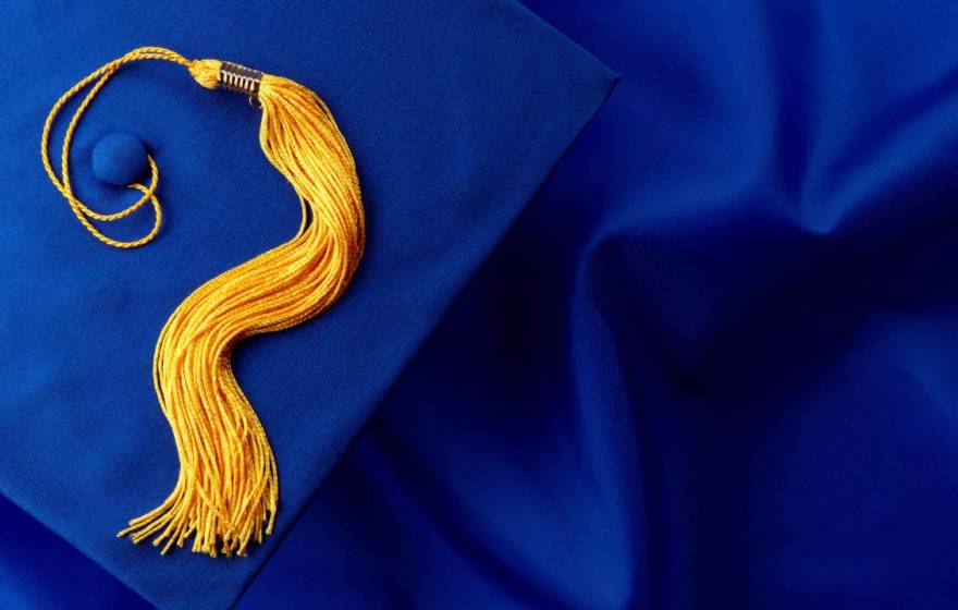 A blue graduation cap with gold tassle