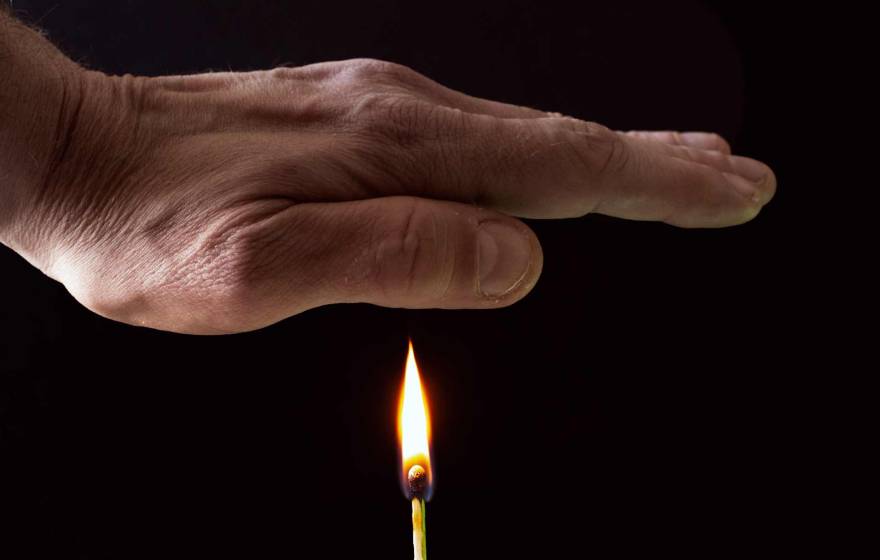 A hand held over a flame from a match