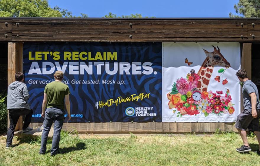 Artists in front of a banner promoting vaccination with a giraffe on it