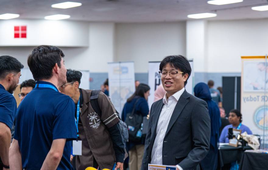 A number of people at a career fair with booths indoors