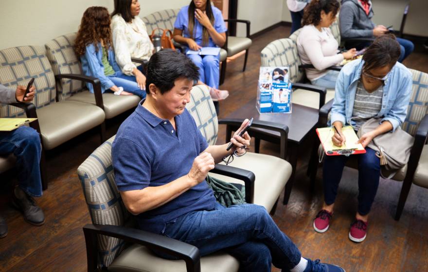 Man looks at his cell phone while waiting at a medical clinic