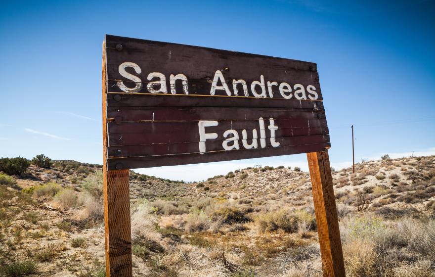 Desert landscape with an old wooden sign reading, San Andreas fault